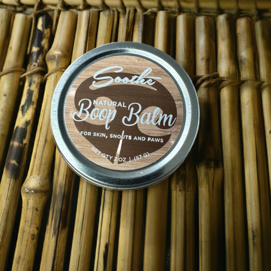 Tin of Soothe Boop Balm with a dog's nose close by on a wooden surface